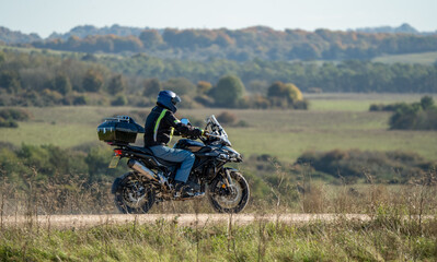 Fototapeta na wymiar a motor cyclist (biker) riding their sports motorbike along a dusty summer stone track