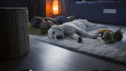 Girl lying on mild carpet with dog, sleeping together at night, feeling relaxed after saturated...
