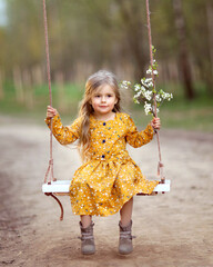 beautiful little girl on a swing with a cherry blossom branch in her hands