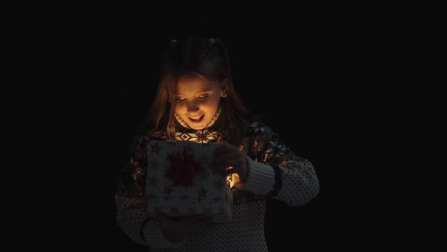 Curious girl in sweater opens magic box with light