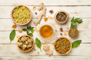 Herbal tea with ingredients on wooden background, top view
