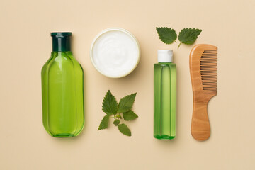 Shampoo with nettle extract on color background, top view