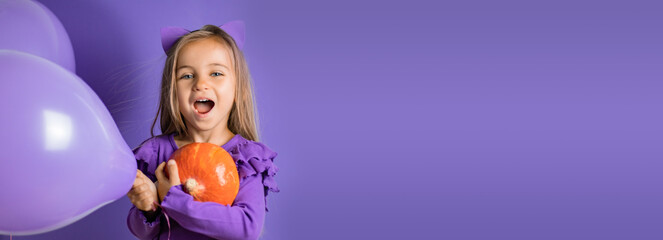 Banner Gorgeous little girl with cat ears, balloons and a pumpkin in her hand on a purple background. Halloween concept