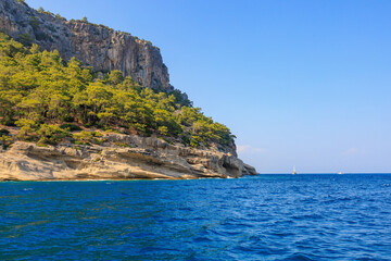Fototapeta na wymiar View of the rocky shore from the sea. Mediterranean Sea in Turkey. Popular tourist places. Background