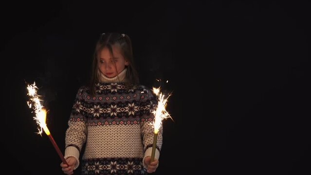 Happy girl is having fun in dark room with sparklers