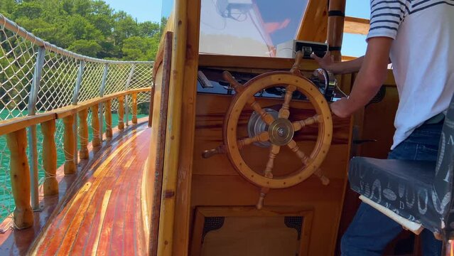 A man steers a ship with a wooden steering wheel, view from the stern of the ship to the sea or river, wooden ship closeup concept, great boat trip
