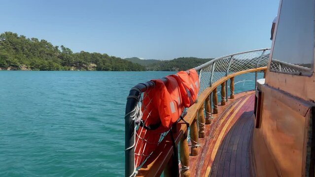 View from the stern of a sailing ship concept, a ship sails on a sea or lake, view from the stern of the ship to aquamarine water closeup concept, mountains in the background 