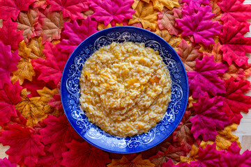 Top view of pumpkin risotto on a wooden table full of maple leaves