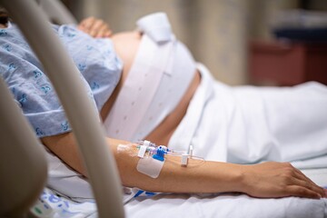 A pregnant woman being monitored in the hospital, connected to a cardiogram and iv. Childbirth and medicine.