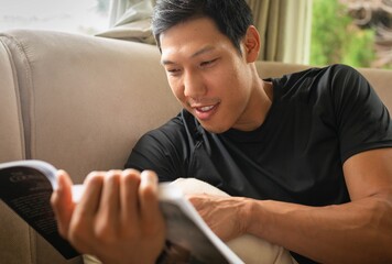 A young man reading a book at home. People learning at home.