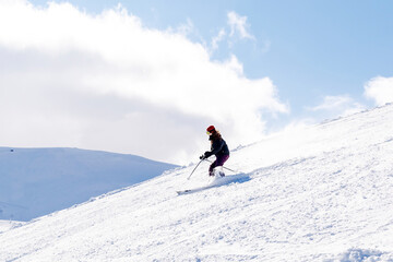 Naklejka na ściany i meble Women in winter overalls skiing on fresh powder snow hill at mountains at winter alpine ski resort