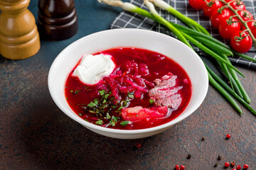 Borscht with sour cream and beef on stone table