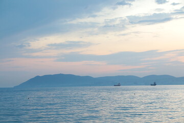 Seascape at dawn with an island in the fog and a ship in the bay