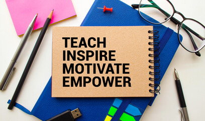 Open notebook with text Teach inspire motivate empower on wooden background.