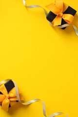 Two black gift boxes with yellow ribbon bow on yellow background with copy space. Black Friday...