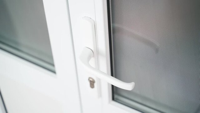 A man locked inside pulls on the handle of a white plastic door. Trapped person can't get out of the room