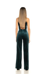 Fototapeta premium Rear view of a fashionable brunette woman with long legs wearing One Piece Jumpsuits trousers,