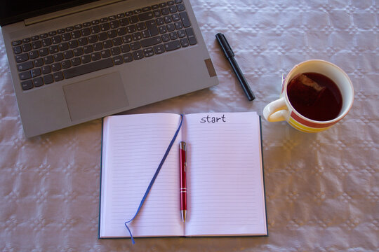 Image of an open diary with pen and marker with the word start. Background a laptop.