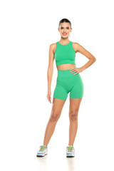 young sporty smiling woman in green shorts and top posing on white background
