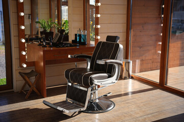 Stylish hairdresser's workplace with professional armchair and large mirror in barbershop. Interior design