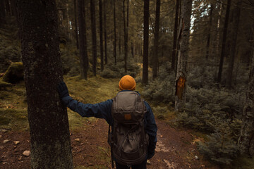 A caucasian man with a backpack hiking in the forest standing at a crossroad. - Powered by Adobe