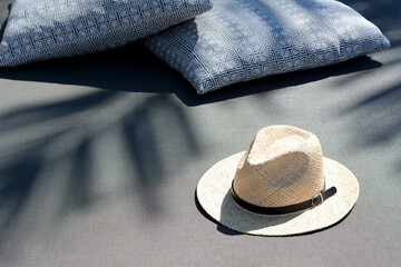 Stylish straw hat and pillows on grey fabric outdoors, space for text