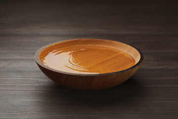 Bowl with clear water on dark wooden table