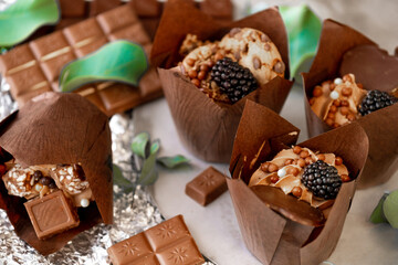 cupcake with blackberry and eucalyptus leaves on silver foil.Chocolate dessert.Assorted sweet table.Sweets and desserts. Baked goods