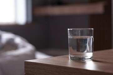 Glass of water on wooden table in room. Space for text