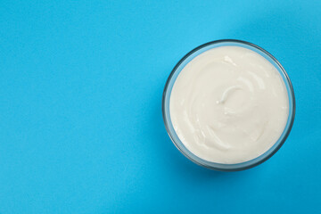 Bowl of tasty organic yogurt on light blue background