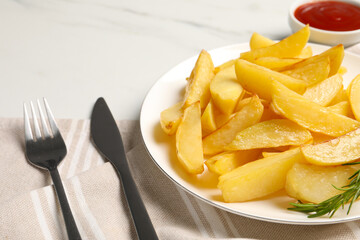 Plate with tasty baked potato wedges, rosemary and sauce on white table, closeup