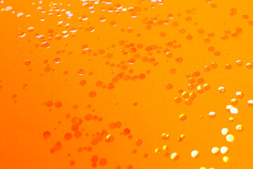 Shiny bright glitter scattered on orange background