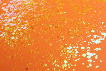 Shiny bright golden glitter on orange background