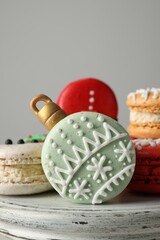 Beautifully decorated Christmas macarons on stand against light grey background, closeup
