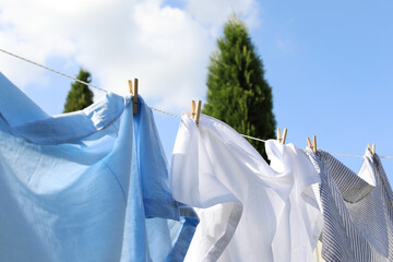 Clean clothes hanging on washing line outdoors, closeup. Drying laundry