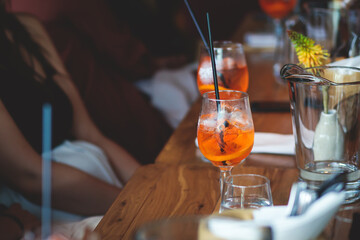 View of alcohol setting on catering banquet table, row line of orange red colored aperitif alcohol cocktails on a party, negroni, spritz and others on decorated catering bouquet table event