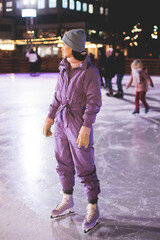 Girl ice skating on the ice rink arena with happy people around, concept of ice skating in winter, winter activities, holiday christmas time, with new year decoration and illumination