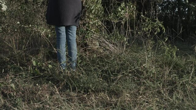 Young Girl in Baggy Clothes Harvests Black Walnuts from the Ground 4K