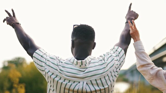 Young adult black man with a firend camping by lake holding arms up in celebratory gesture. Freedom. Horizontal outdoor video. High quality 4k footage