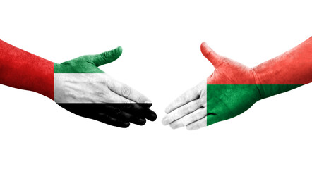 Handshake between Madagascar and UAE flags painted on hands, isolated transparent image.