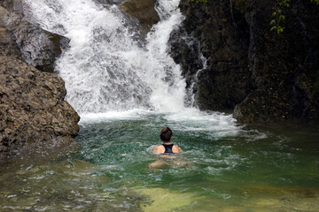 Mid Adult Woman Hiker Swimming under a Waterfall in Wilderness