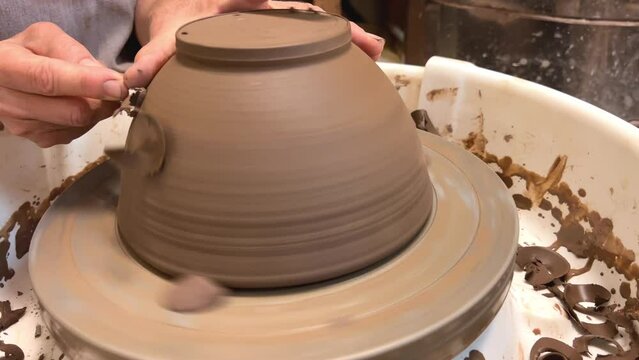 Potter's master class Pottery wheel the art of making pottery for kitchen utensils Women's hands cut off excess clay shavings are visible as if from chocolate Flowing from falling like Serpentine