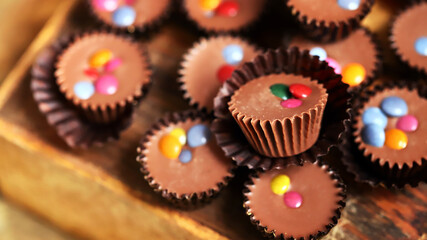 Selective focus. Macro. Small chocolate candies on a wooden board.