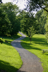 Winding path of a gravel pathway in a city park with many trees.