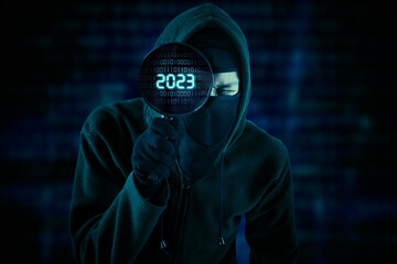 Male hacker looking at 2023 number on magnifier