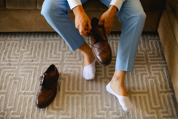 Man wearing a pair of brown leather shoes with laser cut details, wearing blue dress pants