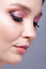 Closeup shot of human woman face. Female with face and eyes beauty makeup with pink smoky eyes eye shadows