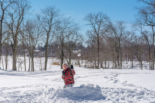 The boy plays with snowballs in the snow