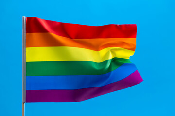 Rainbow flag waving on blue background