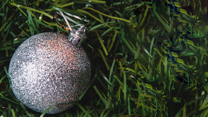 High quality photography. A silver christmas ball on a green christmas tree. Template with silver Christmas design. Christmas season decorations.